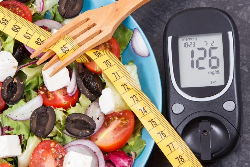 Glucose meter with sugar level, centimeter and greek salad. Diabetes, slimming, healthy lifestyles and nutrition